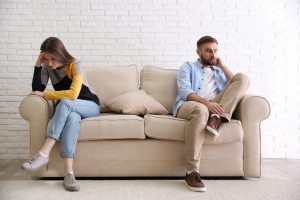 unhappy couple sits on the couch before getting help in couples counseling or marriage counseling in Greenwood, IN at renewed hope counseling services 46143