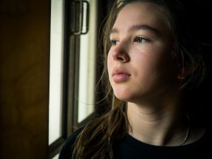 teen girl looking out the window. She is sad before getting teen counseling in greenwood, in at renewed hope counseling 46143