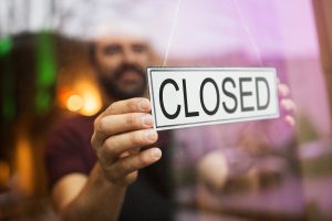 Close up of man holding a "closed" sign on the other side of a store window. The owner has experienced a great deal of trauma related to the lockdown. Renewed Hope Counseling offers trauma treatment in greenwood, in. Contact us today to get in touch with a trauma therapist, and start trauma therapy today. 