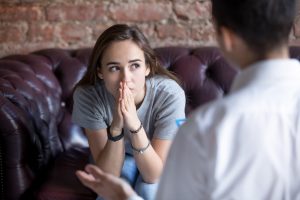 Young adult girl sits in therapists office while resting her hands against her chin. She is concerned about if emdr trauma therapy will actually work, but the emdr clinician reassures her it will. Renewed Hope Counseling offers emdr in greenwood to treat trauma, PTSD, anxiety, depression, and more.