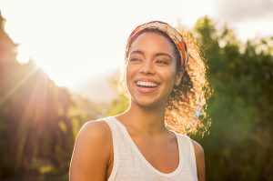 Mixed woman smilies outside as the sun shines behind her. She is feeling better after emdr therapy for ptsd. Renewed Hope Counseling Services offers emdr in greenwood, IN to treat trauma, PTSD, anxiety, performance issues, and more. Meet with an EMDR therapist today.